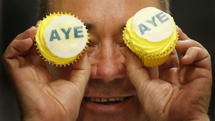 Le chef du Parti national &eacute;cossais, Alex Salmond, tient des g&acirc;teaux pour le "oui" &agrave; l'ind&eacute;pendance ("aye", &agrave; l'&eacute;cossaise), lors de la&nbsp;visite d'une p&acirc;tisserie, le 3 septembre 2014, &agrave; Kilmarnock (Royaume-Uni). (DANNY LAWSON/AP/SIPA)