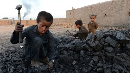 Des enfants taillent des morceaux de charbon à Jalalabad (Afghanistan), le 28 avril 2018. (NOORULLAH SHIRZADA / AFP)