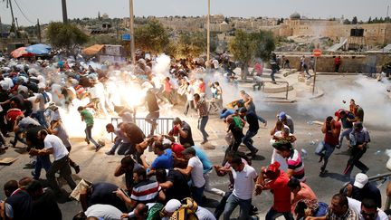 Des Palestiniens courent après des jets de gaz lacrymogène de la part des forces israéliennes, le 21 juillet 2017, dans une rue de Jérusalem. (AMMAR AWAD / REUTERS)