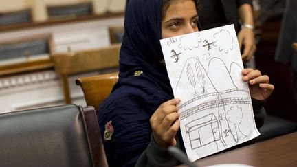 Une petite fille pakistanaise de 9 ans montre un dessin sur lequel elle a repr&eacute;sent&eacute; l'attaque d'un drone tuant sa grand-m&egrave;re lors d'une conf&eacute;rence &agrave; Washington (Etats-Unis), le 29 octobre 2013. (EVAN VUCCI / AP / SIPA)