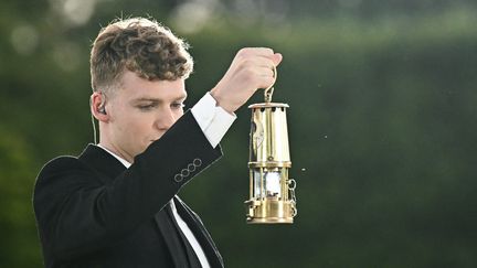 Le nageur français Léon Marchand éteint la vasque olympique, le 11 août 2024, dans le Jardin des Tuileries, à l'occasion de la cérémonie de clôture. (LOIC VENANCE / AFP)