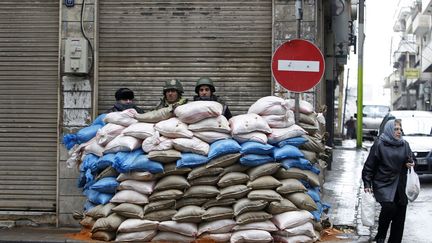 Des soldats syriens montent la garde &agrave; un point de contr&ocirc;le dans une rue de Homs, le 23 janvier 2012. (AHMED JADALLAH / REUTERS)