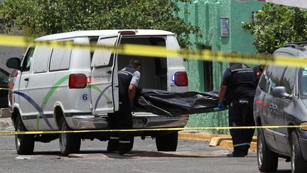 Du personnel médico-légal charge le corps d'une personne tuée lors d'une opération de police qui a fait trois morts à&nbsp;Guadalajara, au Mexique, le 10 juin 2018.&nbsp; (ULISES RUIZ / AFP)