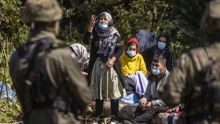 Une femme parle à un garde-frontière polonais dans le village d'Usnarz Gorny, près de Bialystok, dans le nord-est de la Pologne, à proximité de la frontière avec la Biélorussie, le 20 août 2021.&nbsp; (WOJTEK RADWANSKI / AFP)