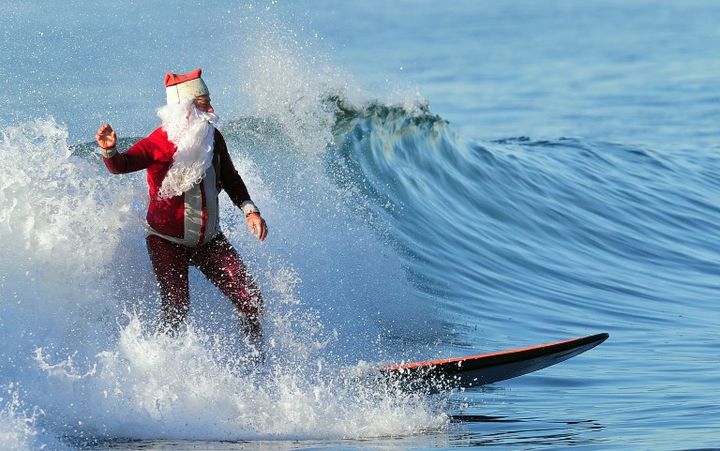 Le p&egrave;re No&euml;l arrive en surf sur une plage de Los Angeles (Californie)&nbsp;le 24 d&eacute;cembre 2011. (FREDERIC J. BROWN / AFP)