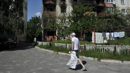 Un habitant passe devant un immeuble résidentiel brûlé à Makariv, à l'ouest de Kiev, le 11 juin 2022. (SERGEI CHUZAVKOV / AFP)