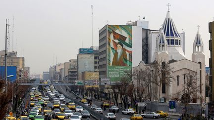 La cathédrale arménienne Saint Sarkis, à côté d'un bâtiment sur lequel se trouve un portrait de&nbsp;l'ayatollah Ruhollah Khomeini, le 1er janvier 2020 à Téhéran (Iran). (ATTA KENARE / AFP)