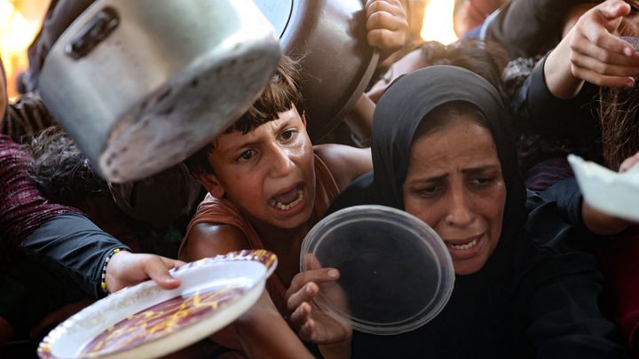 Des Palestiniens tendent leurs assiettes pour recevoir un repas préparé par des volontaires à Beit Lahia, dans le nord de la bande de Gaza, le 14 août 2024. (OMAR AL-QATTAA / AFP)