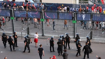 La police patrouille devant la clôture alors que les supporters sont empêchés d'entrer avant la finale de la Ligue des champions de l'UEFA entre Liverpool et le Real Madrid au Stade de France à Saint-Denis, au nord de Paris, le 28 mai 2022. (THOMAS COEX / AFP)