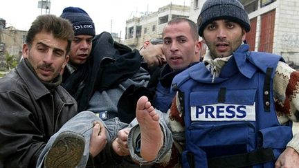 Le photographe palestinien de l'agence AP, Nasser Shiyoukh, blessé et assisté par ses collègues près d'Hébron le 16 février 2007 (AFP - HAZEM BADER )