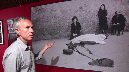 Christian Buffa, commissaire de l'exposition "Les îles du milieu" devant cette photo de Franco Zecchin qui avait créé la polémique. Dans la flaque de sang, on aperçoit le reflet du visage d'une femme. "Aujourd'hui, ce genre d'image serait censurée". (F. Rombaldi / France Télévisions)