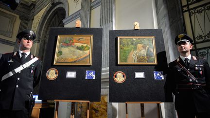 Des carabiniers italiens encadrent les deux tableaux volés à Londres en 1970 et découverts en Italie, "Fruits sur une table ou nature morte au petit chien" de Gauguin et&nbsp;"La femme aux deux fauteuils" de Bonnard, le 2 avril 2014 (ANDREAS SOLARO / AFP)