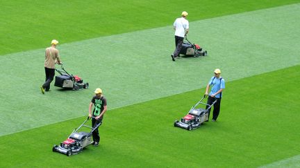 Des employ&eacute;s tondent la pelouse du stade Arena &agrave; Lviv (Ukraine) avant le d&eacute;but de l'Euro, le 7 juin 2012. (YURIY DYACHYSHYN / AFP)