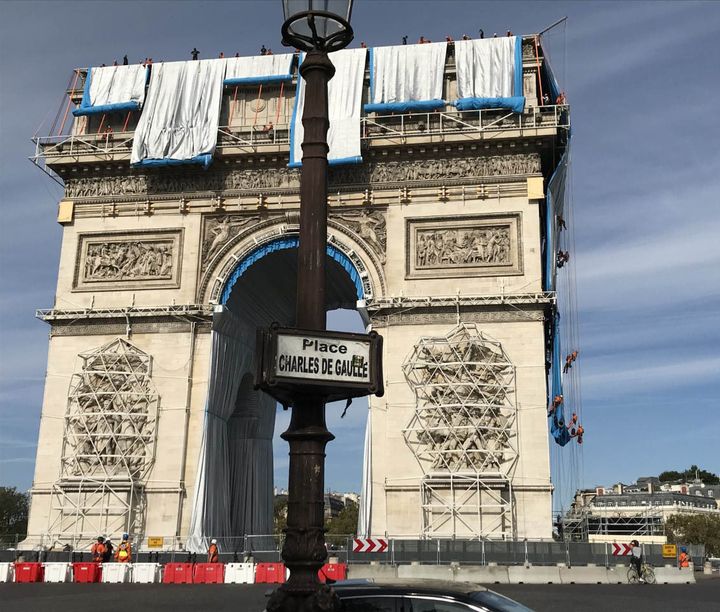 Le premier déroulé de tissu de l'empaquetage posthume de l'Arc de Triomphe par Christo, avec l'équipe de cordistes à droite du monument, dimanche 12 septembre 2021 à Paris. (VALERIE GAGET - FRANCE TELEVISIONS)