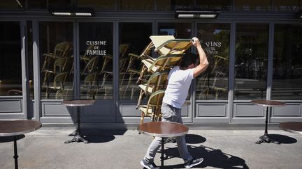 Un barman range une terrasse (illustration). (JULIEN DE ROSA / EPA)