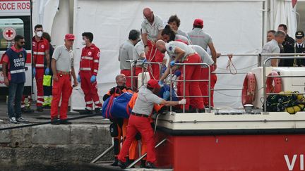 Des sauveteurs transportent un corps dans le port de Porticello, près de Palerme (Italie), le 22 août 2024, trois jours après le naufrage du voilier "Bayesian". (ALBERTO PIZZOLI / AFP)