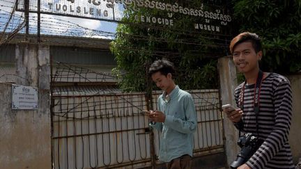 Deux Cambodgiens chassent des Pokémons dans l'ancien camp de détention et de torture dirigé par les kmers rouges. (TANG CHHIN SOTHY / AFP)