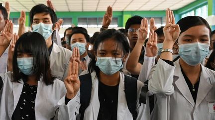 Des étudiants en médecine font le salut à trois doigts, emblème de la mobilisation contre le coup d'Etat militaire, lors des obsèques de Khant Nyar Hein, abattu pendant une manifestation, le 16 mars 2021 à Rangoun (Birmanie). (AFP)