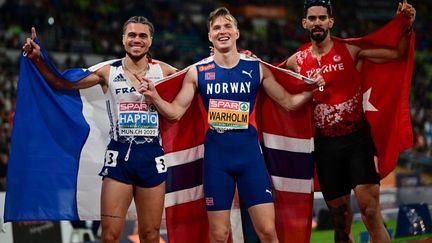 Le médaillé d'argent français Wilfried Happio, en compagnie du&nbsp; médaillé d'or Karsten Warholm et du médaillé de bronze Yasmani Copello après la finale du 400 m haies masculin, le 19 août 2022. (INA FASSBENDER / AFP)