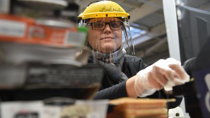 Une hôtesse de caisse se protège du coronavirus dans un magasin à Illers-Combray (Eure-et-Loir). Photo d'illustration. (JEAN-FRANCOIS MONIER / AFP)