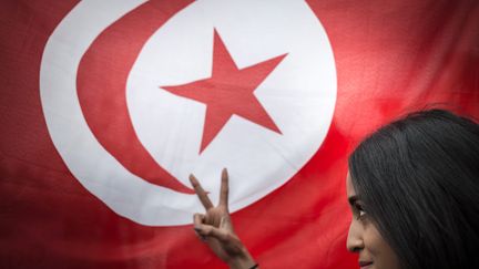 Une femme posant devant le drapeau tunisien, place de la République à Paris. Photo d'illustration. (XAVIER DE TORRES / MAXPPP)