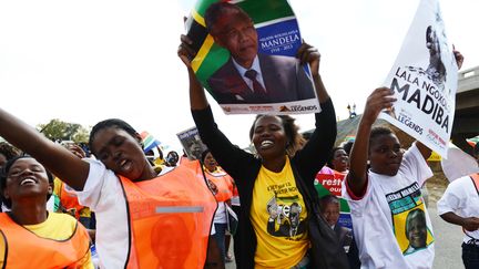 Des Sud-Africains acclament&nbsp;le fourgon mortuaire transportant le cercueil de Nelson Mandela, &agrave; Qunu (Afrique du Sud), le 14 d&eacute;cembre 2013. (ROBERTO SCHMIDT / AFP)