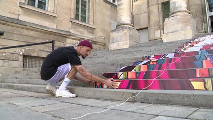 L'artiste poitevin Piko en pleine installation sur les marches du Palais des Ducs à Poitiers. (CAPTURE D'ÉCRAN FRANCE 3 / A. Morel)