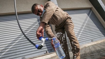 Un Palestinien remplit une bouteille d'un générateur d'eau alimenté par l'énergie solaire, dans la ville de Khan Yunis&nbsp;à Gaza, le 16 novembre 2020. (SAID KHATIB / AFP)