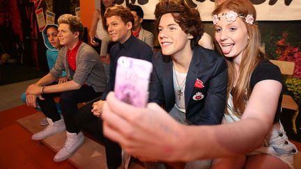 Une adolescente se prend en photo avec les statues de cire du groupe britannique One Direction, au mus&eacute;e de Madame Tussauds, &agrave; Sydney (Australie).&nbsp; (NEWSPIX / REX / SIPA )