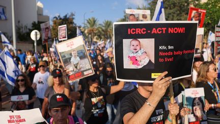 A protester carries a sign showing Kfir Bibas' photo during a rally to demand his release, November 16, 2023 in Modiin, Israel.  (MENAHEM KAHANA / AFP)