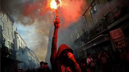 Un jeune manifestant tient une fus&eacute;e de d&eacute;tresse dans les rues de Lisbonne (Portugal). (PATRICIA DE MELO MOREIRA / AFP)