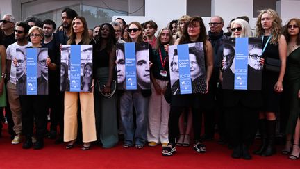 Des membres du jury de la 79e Mostra de Venise, dont l'actrice américaine Julianne Moore et la réalisatrice française Audrey Diwan, montrent des phoros de réalisateurs emprisonnés, dont les Iraniens Jafar Panahi et Mohamed al-Ahmed, le 9 septembre 2022. (TIZIANA FABI / AFP)