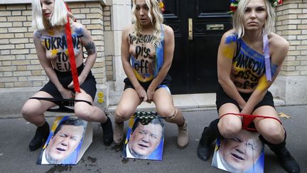 Inna Shevchenko (C) et d'autres militantes Femen urinent sur une photo du pr&eacute;sident ukrainien&nbsp;Viktor Ianoukovytch devant l'ambassade ukrainienne &agrave; Paris, le 1er d&eacute;cembre 2013. (THOMAS SAMSON / AFP)