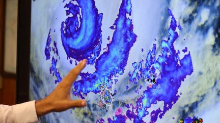 Un météorologue de Météo France montre le cyclone Belal sur un écran, quelques heures avant qu'il frappe La Réunion, le 14 janvier 2024 à Paris. (RICHARD BOUHET / AFP)