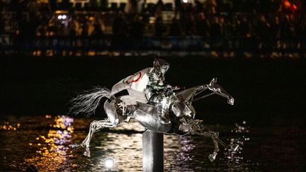 La cavalière, portant le drapeau du Comité International Olympique, sur un cheval de métal sur la Seine lors de la cérémonie d'ouverture des Jeux Olympiques de Paris 2024 le 26 juillet 2024 à Paris. (TOM WELLER/VOIGT / GETTY IMAGES EUROPE)