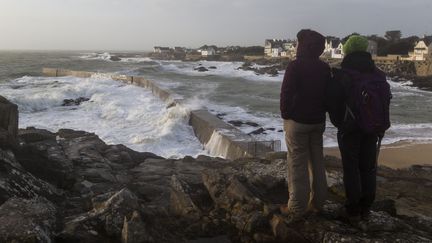 Deux promeneurs observent de fortes vagues s'abattre sur une jetée au Croisic (Loire-Atlantique), le 30 décembre 2017. (CAROLINE PAUX / CROWDSPARK / AFP)