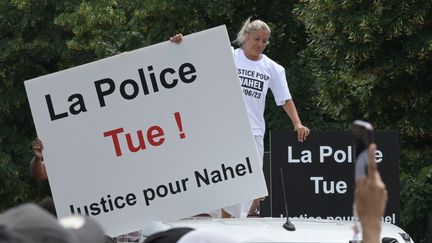 Mounia, la mère de Nahel, tient une pancarte avec l'inscription "La police tue ! Justice pour Nahel", lors d'une marche commémorative pour son fils, le 29 juin 2023, dans la banlieue parisienne de Nanterre. (ALAIN JOCARD / AFP)