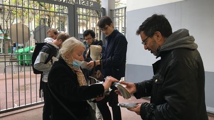 Françoise, soutien de Yannick Jadot, distribue des tracts aux militants lors d'un porte-à-porte, dans le 14e arrondissement de Paris, le 30 mars 2022. (MARGAUX DUGUET / FRANCEINFO)