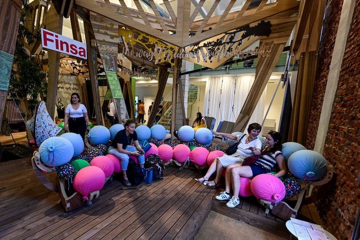 Des visiteurs installés sur un canapé de la société de design espagnole Finsa exposé au Salon du design de Milan, le 9 juin 2022. (MIGUEL MEDINA / AFP)