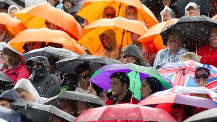 Les spectateurs des &eacute;preuves de beach volley, sous la pluie, dimanche 29 juillet 2012 lors des JO de Londres. (NEIL HALL / REUTERS)