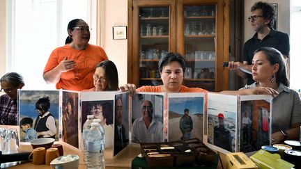 Des membres de la délégation inuite montrent des photos de victimes déclarées à Lyon, le 14 septembre 2022. (JEFF PACHOUD / AFP)