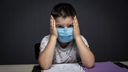 Un écolier masqué fait ses devoirs pendant le deuxième confinement en France le 31 octobre 2020. (MAXIME FRAISSE / HANS LUCAS / AFP)