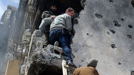 le photographe de guerre britannique descend d'un bâtiment en ruine à Misrata, aidé par des rebelles libyens, après que des coups de feu ont retenti à l'intérieur. La ville a été assiégée par les forces loyalistes de Kadhafi, le 20 avril 2011.

Peu de temps après, il sera tué avec son confrère américain Chris Hondros lors d’un bombardement sur la ville. 

Voir leur travail* (AFP PHOTO / PHIL MOORE)