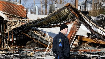 Un policier surveille les ruines d'un b&acirc;timent de&nbsp;Ferguson (Etats-Unis),&nbsp;incendi&eacute;&nbsp;dans la nuit du 24 au 25 novembre. (JIM YOUNG / REUTERS)