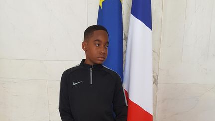 Yannel pose devant des drapeaux à l'Elysée, le 10 juillet 2018, avant de s'envoler pour Saint-Pétersbourg où il assistera au match France-Belgique aux côtés d'Emmanuel Macron. (DR)