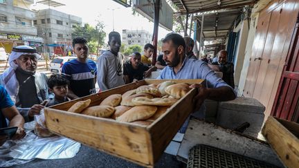 Palestinians queue in front of a bakery to buy bread as the Israeli army bombards Gaza City, the main city of the Gaza Strip enclave, on October 14, 2023. (ABED RAHIM KHATIB / ANADOLU / AFP)