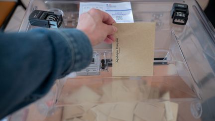 Un électeur glisse un bulletin dans l'urne d'un bureau de vote à Paris lors du premier tour des élections législatives, le 12 juin 2022. (SOPHIE LIBERMANN / HANS LUCAS / AFP)