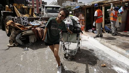 Une femme tire un caddie contenant ses affaires alors que des ouvriers d&eacute;montent des cabanons dans un bidonville de Sao Paulo (Br&eacute;sil), le 15 janvier 2014. (NACHO DOCE / REUTERS)