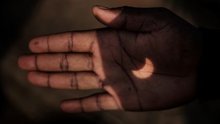 L'ombre de l'éclipse est projetée sur la main d'un homme à travers des jumelles, à Nairobi (Kenya). (YASUYOSHI CHIBA / AFP)