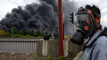 Un habitant de Rouen porte un masque à gaz, à proximité de l'usine Lubrizol en feu, le 26 septembre 2019. (BEAUFILS / SIPA)